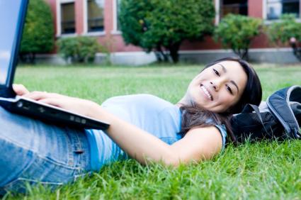 Student with laptop in grass